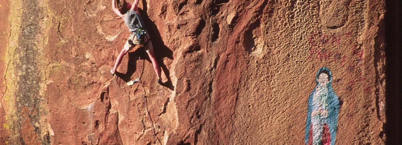 Climber in Penitente Canyon adjacent to pictograph of the Virgen de Guadalupe